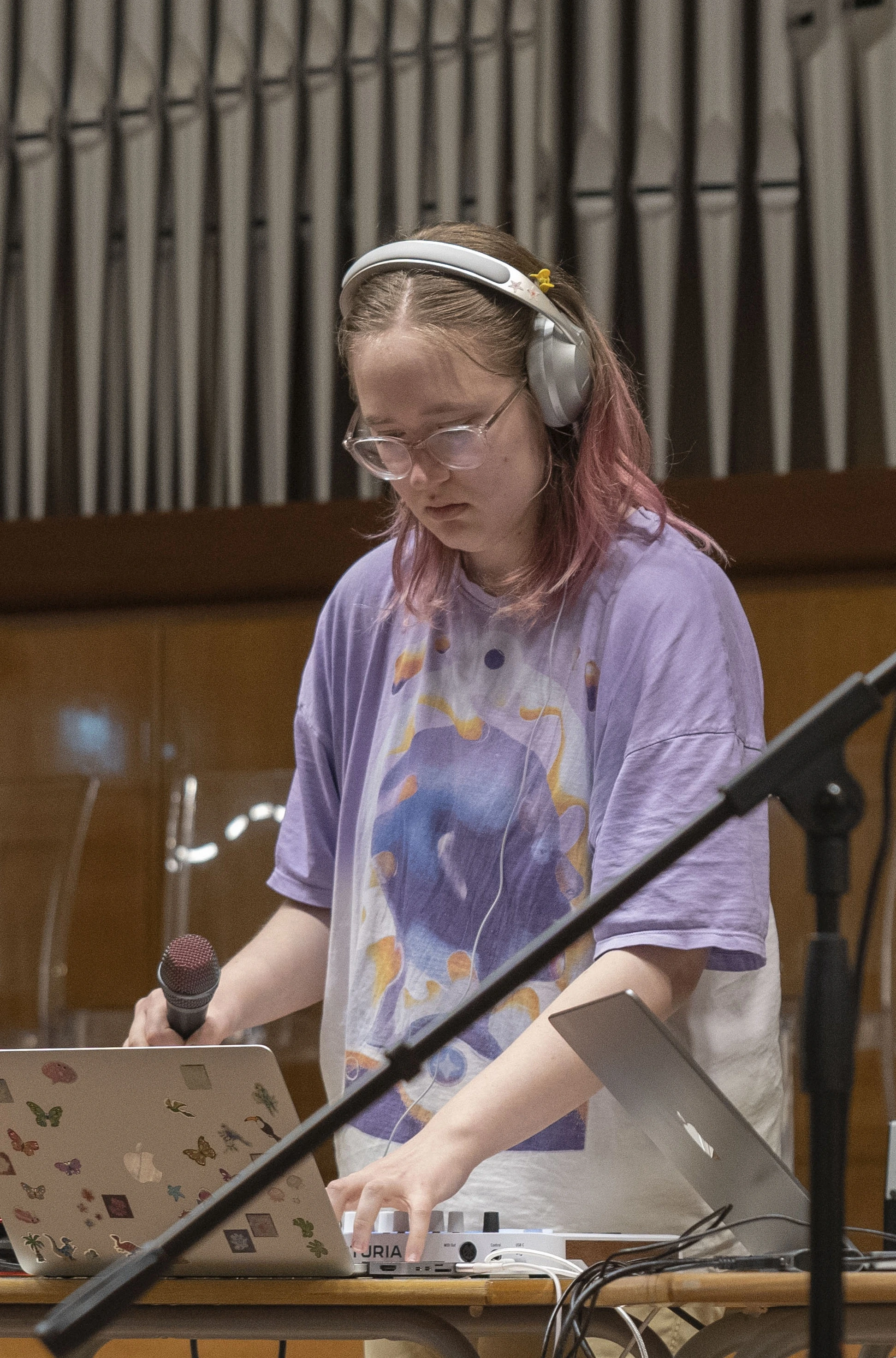 A picture of me (Magda) working at a computer with a microphone in hand in a classical auditorium.